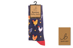 A pair of Bartleby Bamboo Funky Socks hanging on a black hanger against a white background, next to a small brown brand card. The socks are navy blue with a pattern of colorful chickens and a red toe.